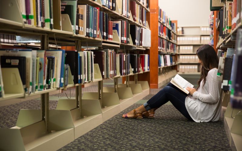 Girl reading on the floor in a library